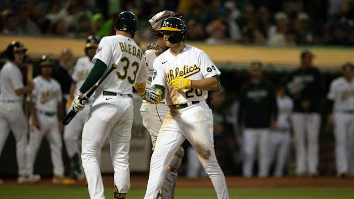 Oakland Athletics second baseman Zack Gelof (20) gets a congratulatory handshake from JJ Bleday (33) after hitting his first career home run during the seventh inning against the Houston Astros at Oakland-Alameda County Coliseum.